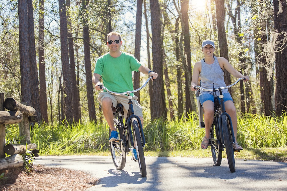 Happy Couple riding bikes together on a bike path in the woods.