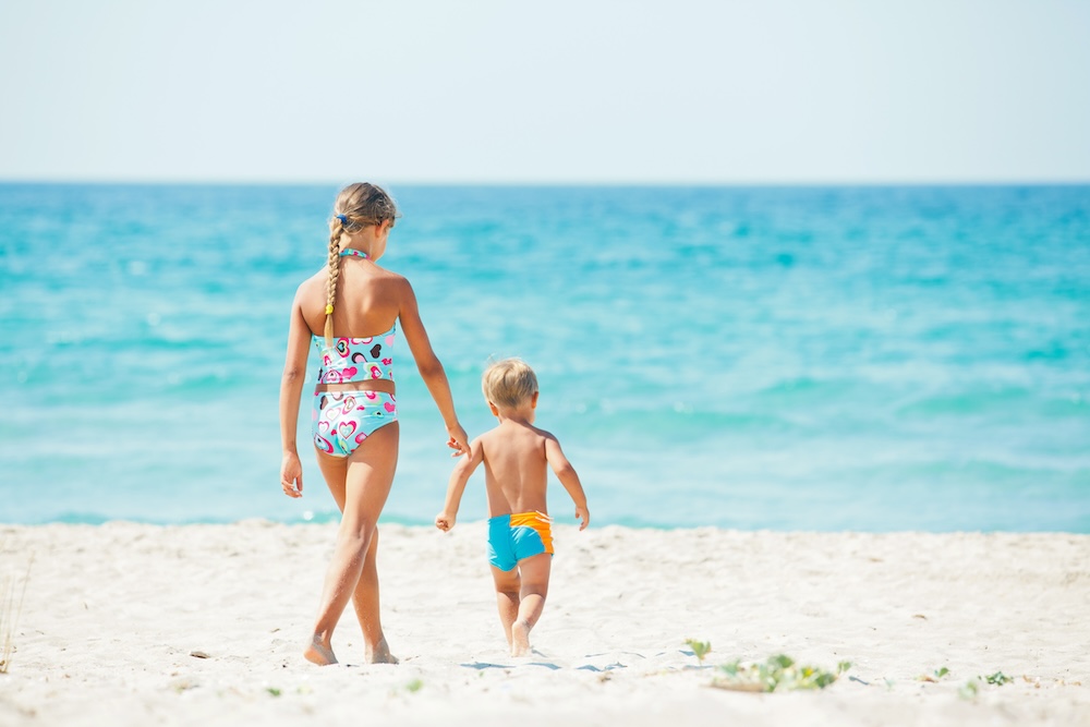 Young girl and boy playing happily at pretty beach.